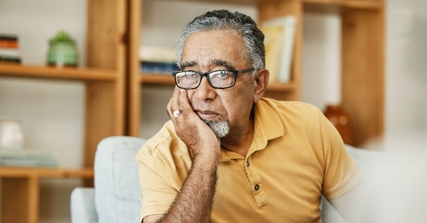 Older man looking worried resting his face on his hand