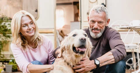 Couple in their 60s petting a dog