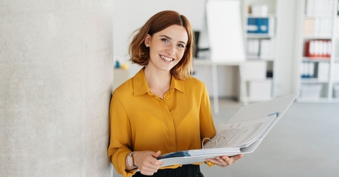 Young office worker in a yellow top holding a binder