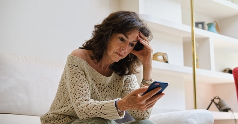 Concerned mature woman on couch looking at phone
