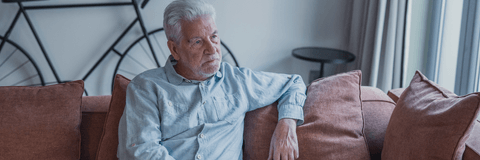 Older man sitting on couch looking distressed