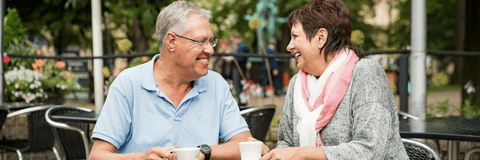 Couple in their 60s sitting outside having coffee