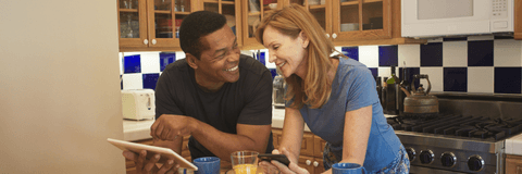 Couple in their 50s looking at tablet in kitchen