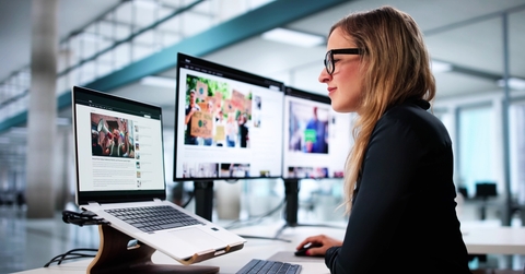 Woman reading articles on several computer screens