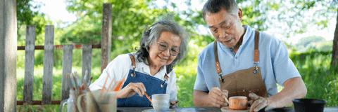 Senior couple doing pottery outside home