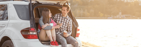 Couple sitting in car on beach while traveling
