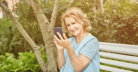 Senior retiree woman looking at investments on phone