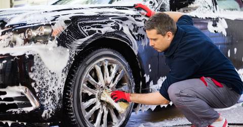 Man worker washing car&#x27;s alloy wheels on a car wash