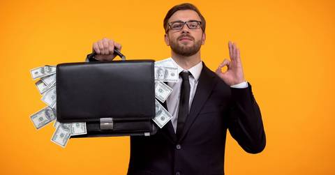 man wearing glasses and holding a money bag