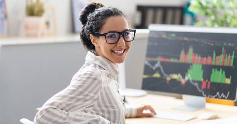 Happy woman in front of computer with stocks stats