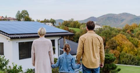family looking at their house with installed solar panels
