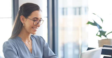 young happy businesswoman wearing glasses working on laptop on table