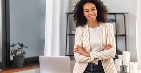 office worker stands with crossed arms near a desk