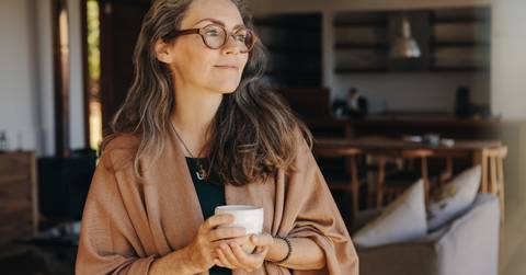 thoughtful senior woman holding a tea cup at home