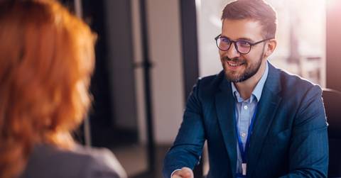 male bank manager in suit shaking hands with female client 