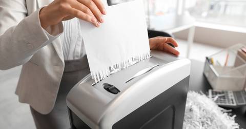 secretary destroying paper sheet using shredder in office