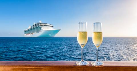 two glasses of champagne on wooden railing at sunset