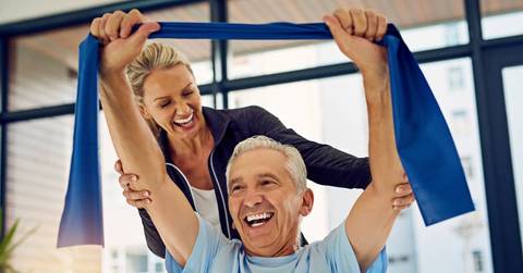 Physical therapist helping a senior patient stretch with a stretch band